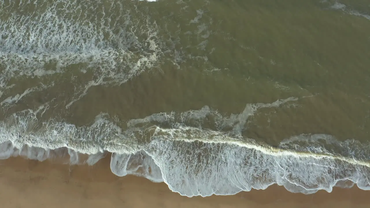 Powerful agitated sea with high waves constantly crashing on an empty secluded beach