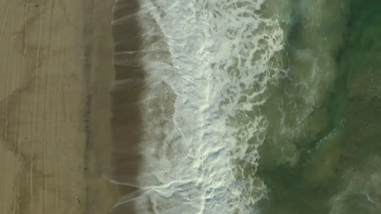 Drone top shot of sea water waves hits beachside