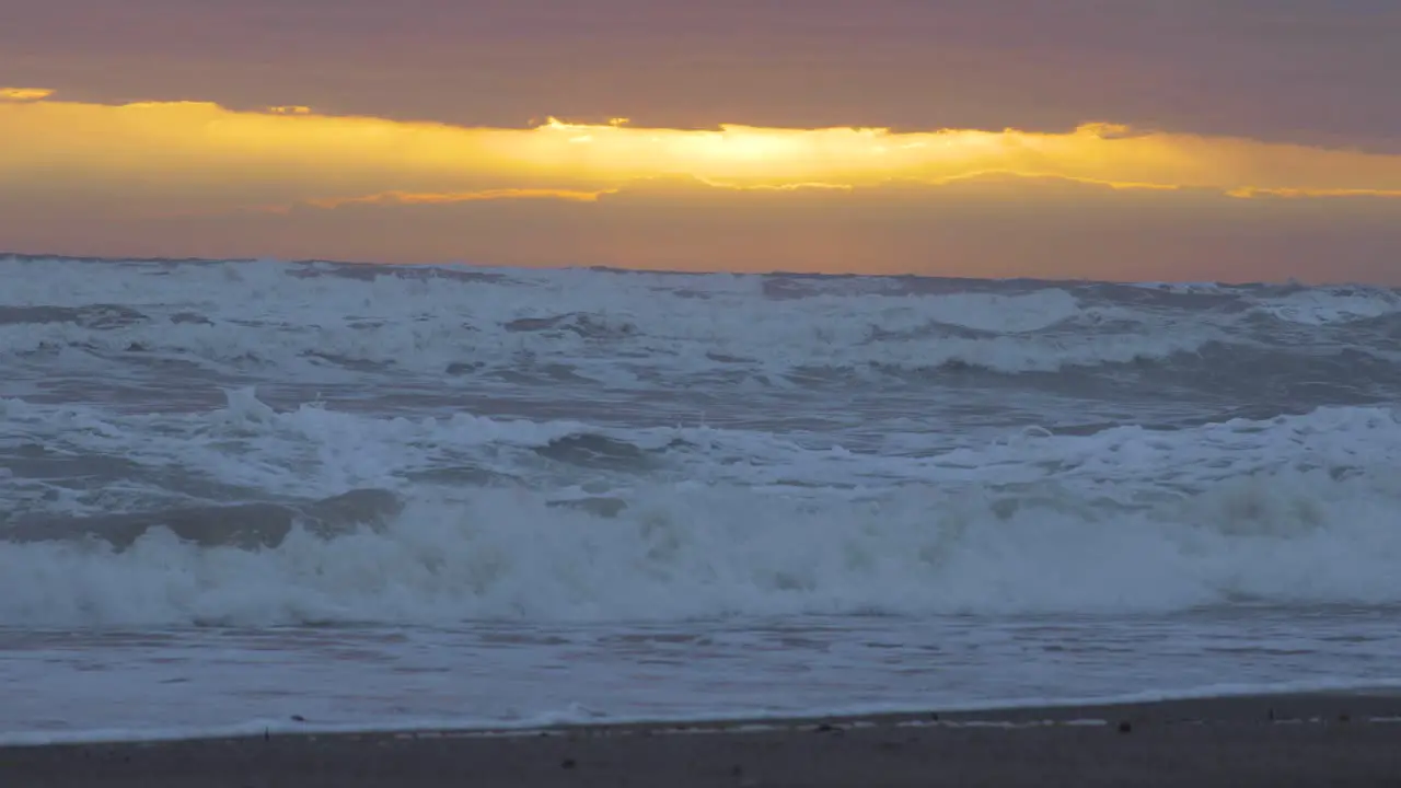 The sun starts to shine through the clouds above the ocean on a beach just after a storm