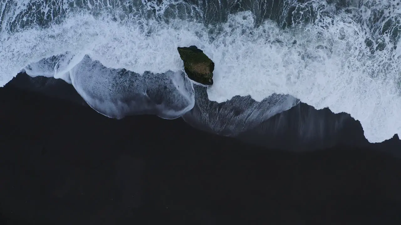 Aerial top down shot of waves of Ocean splashing against Stapavík sea stack in Iceland