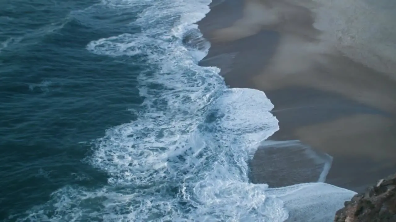 Big waves break on the coast at Nazare in Portugal taken from above on a late summer afternoon