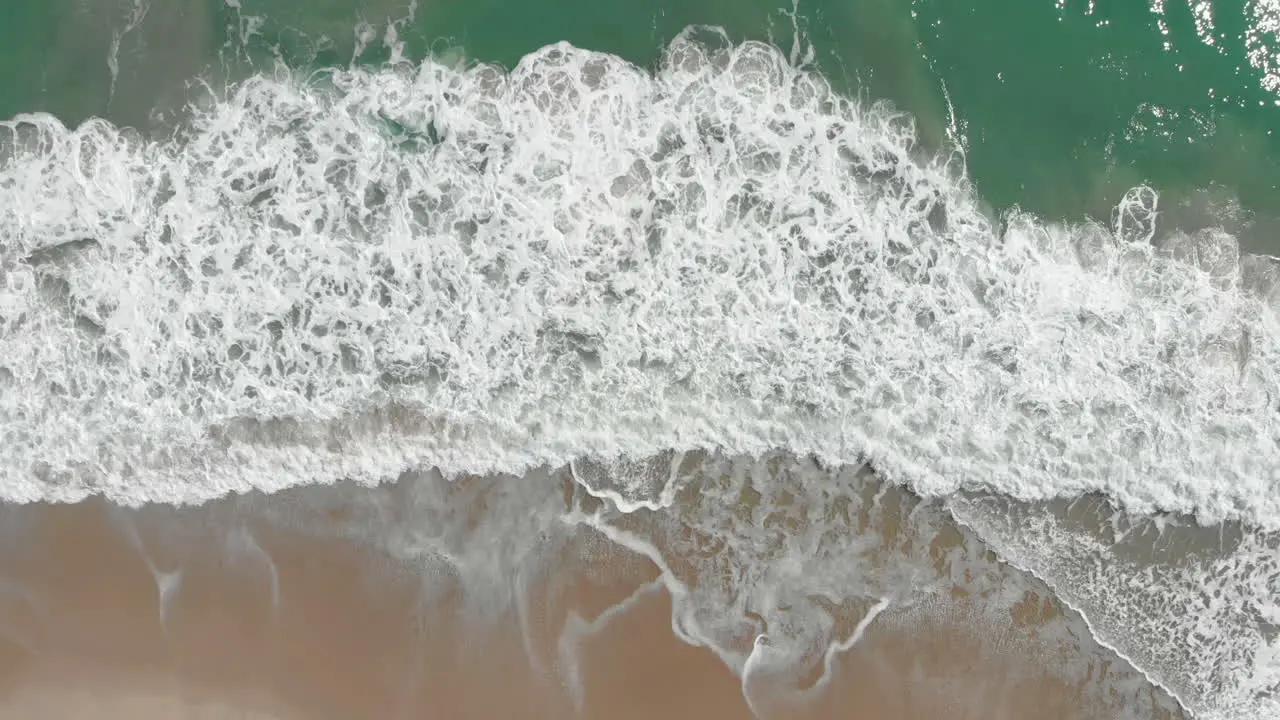 Aerial top down shot of Splashing ocean Waves And Beach At Gold Coast