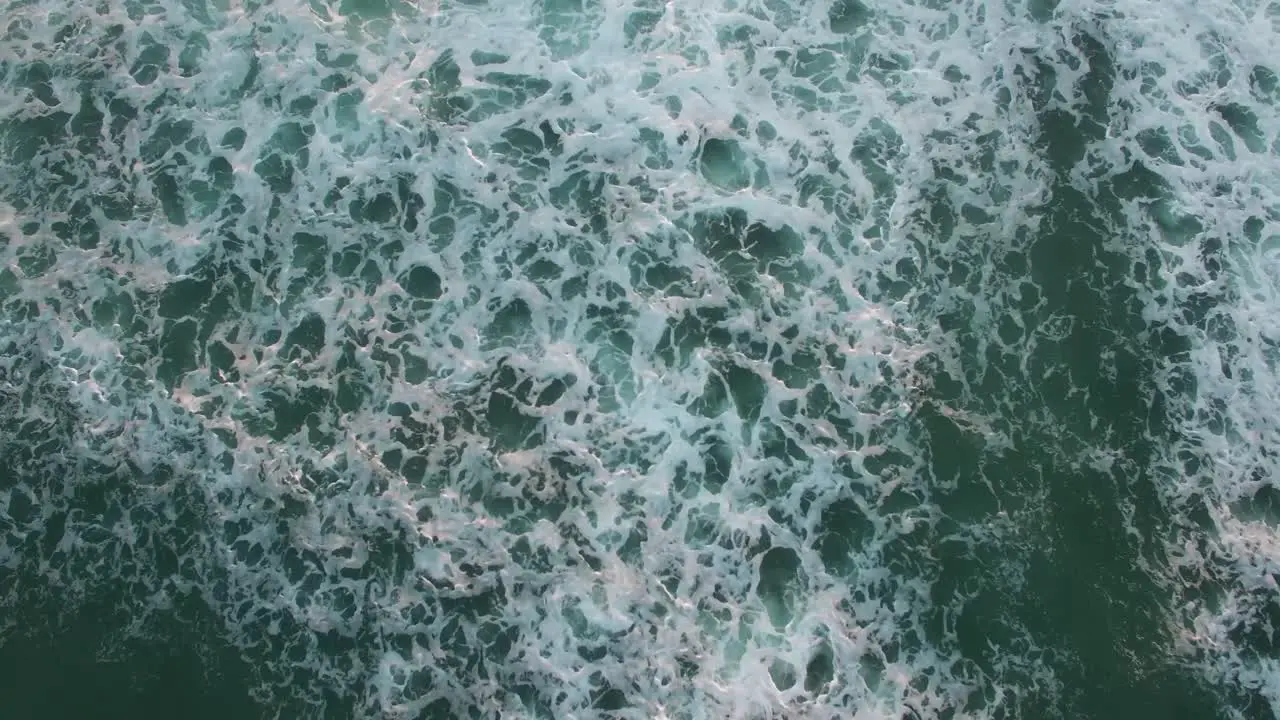 Aerial perspective looking straight down at the ocean with waves rolling in