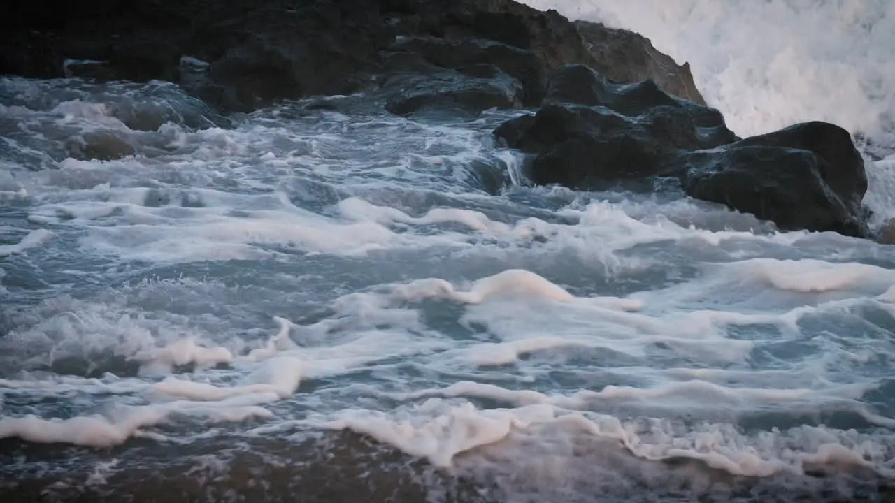 Blue waves roll into the coast of Hawaii in slow motion and break over rocks 1