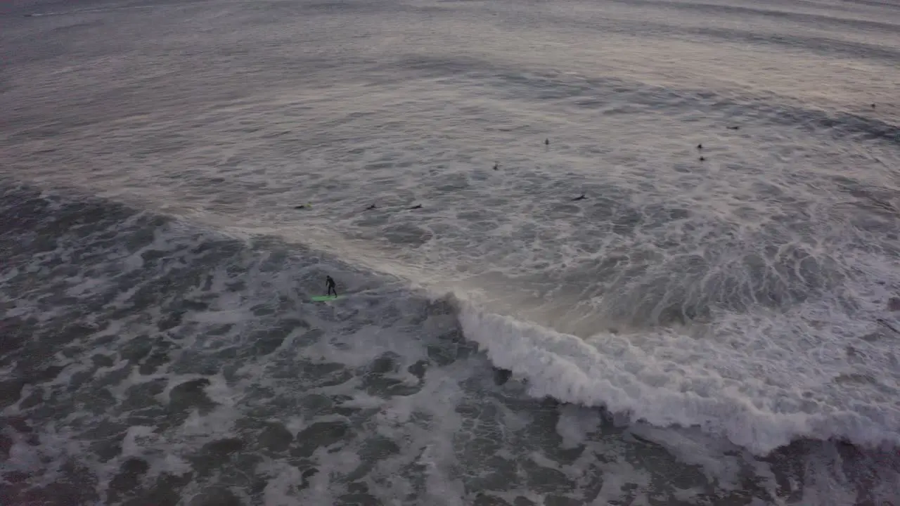 Aerial drone view following some surfers catching waves on coast of Portugal-1