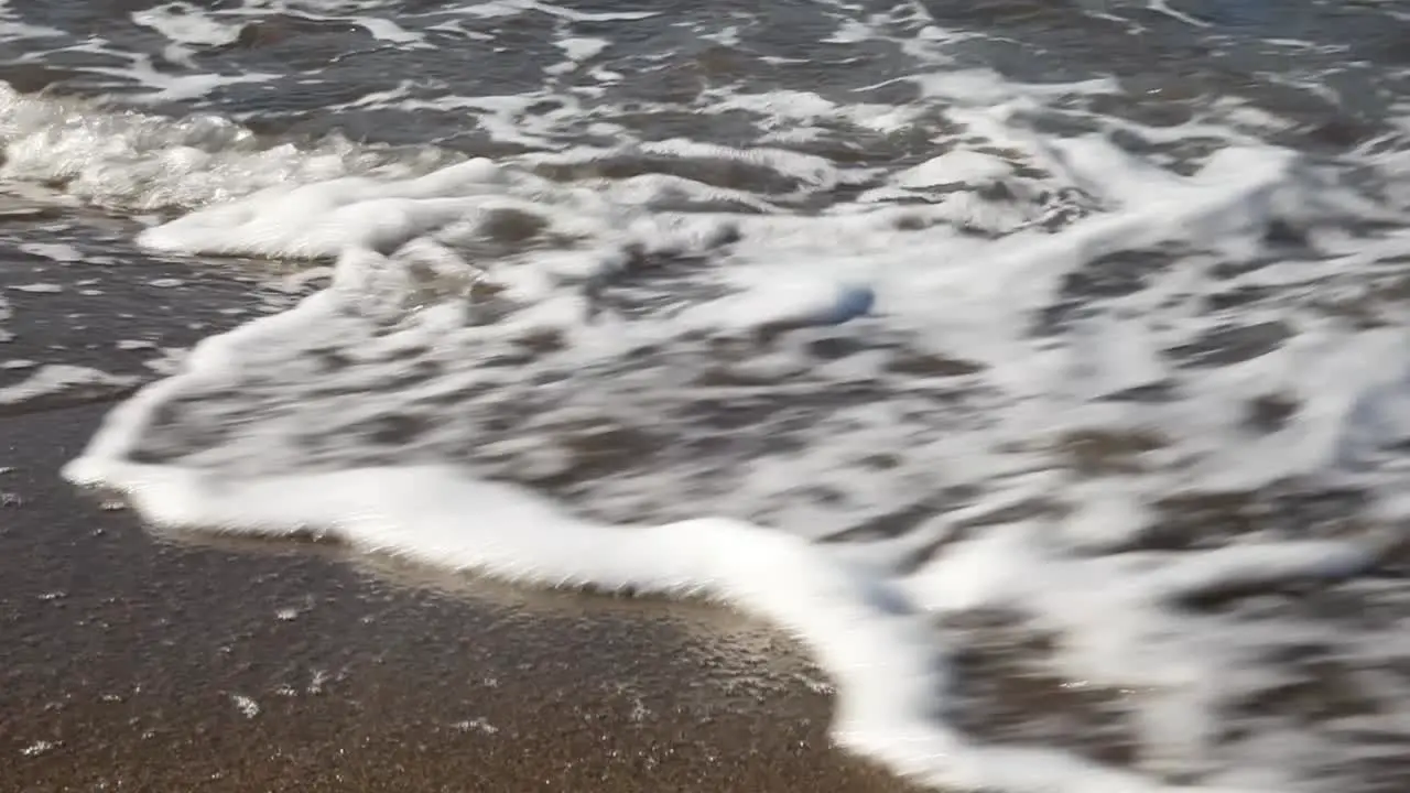 Close Up on Rolling Waves at a Sandy Beach