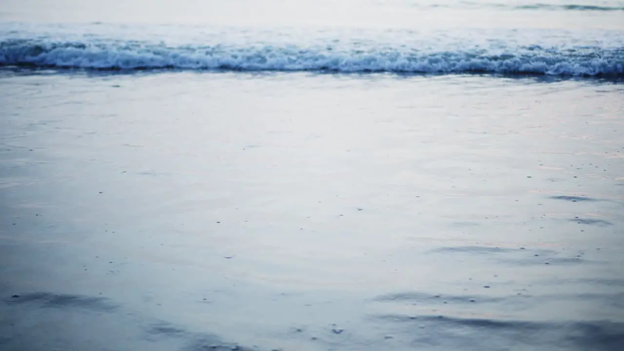 Slow-motion Close up of waves moving onto the beach at dusk