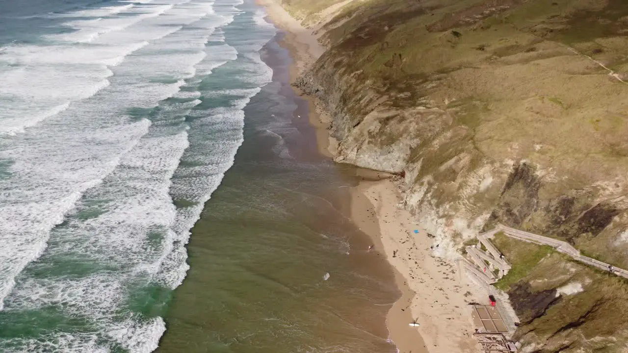 A lengthy golden sandy beach with beautiful green waves crashing ashore in Cornwall