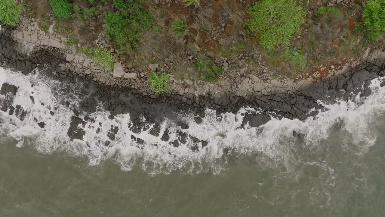 Slow motion aerial footage top down of ocean waves crashing into rocks