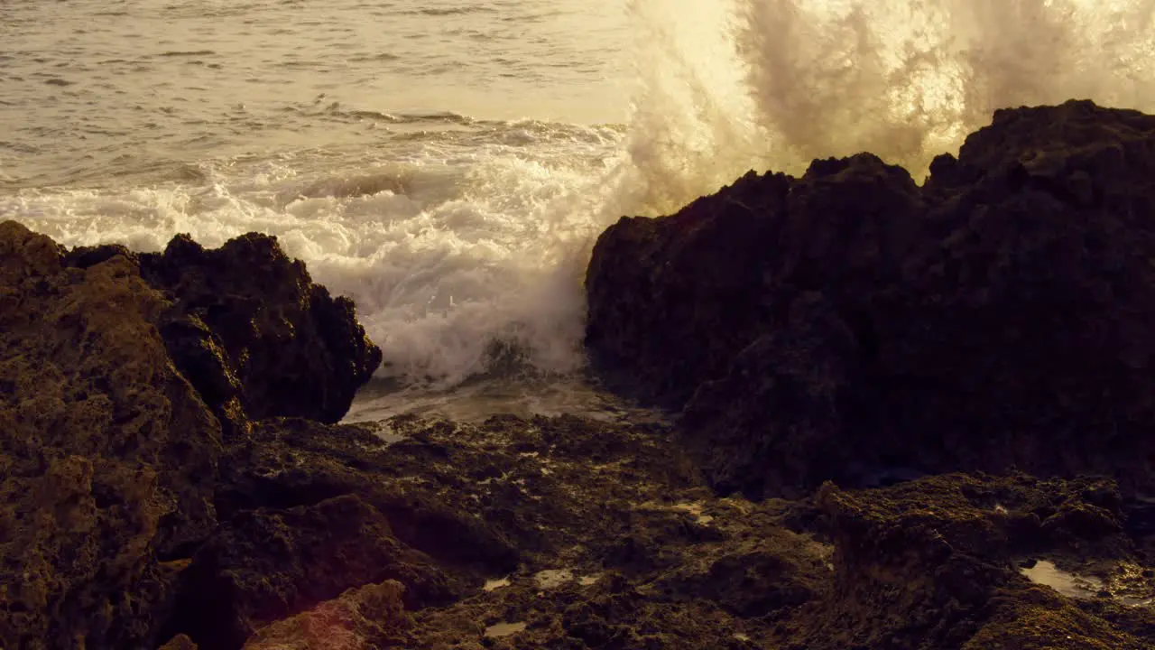 Majestic Slow Motion Ocean Waves Crash on Sharp Rocks during Golden Hour Low Angle Static