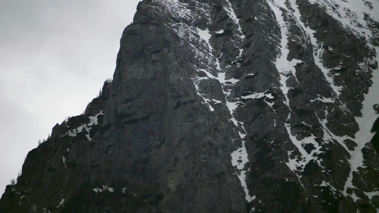 Tilt-up camera movement showing a dark steep mountain ridge with some patches of snow in the Bucegi Carpathian Mountains