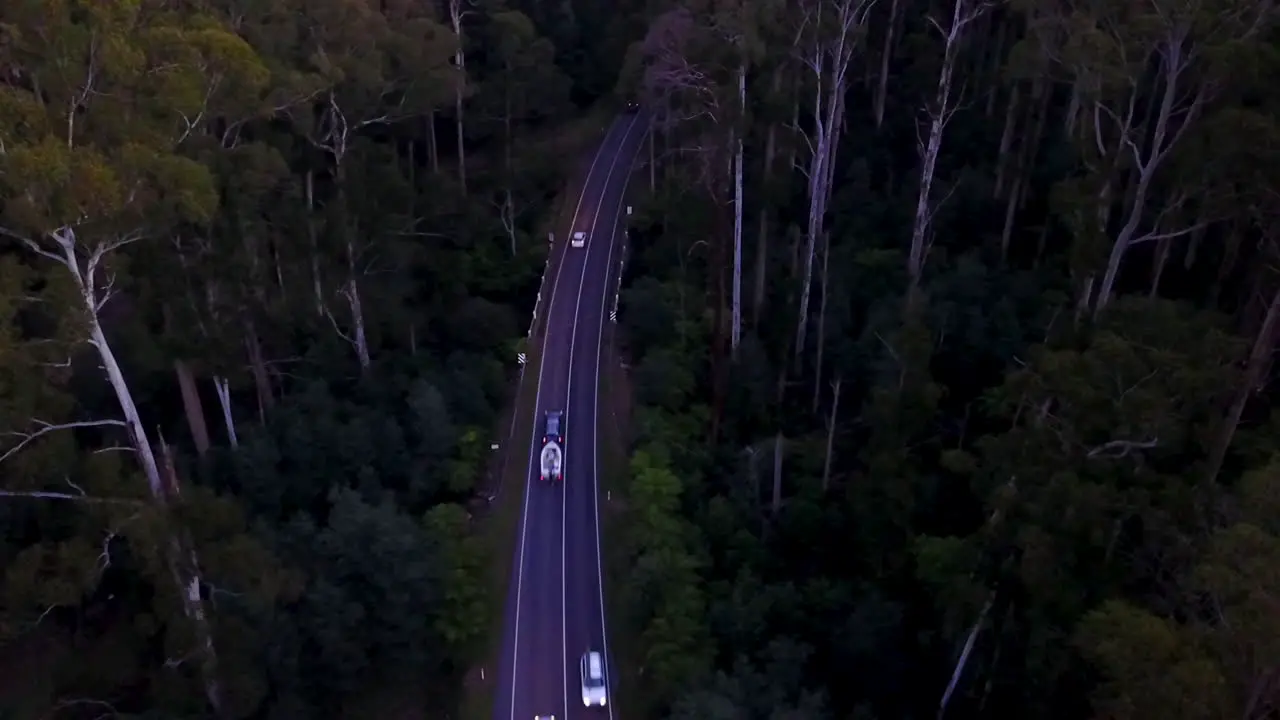 Aerial footage of dark forest road with many cars at dusk