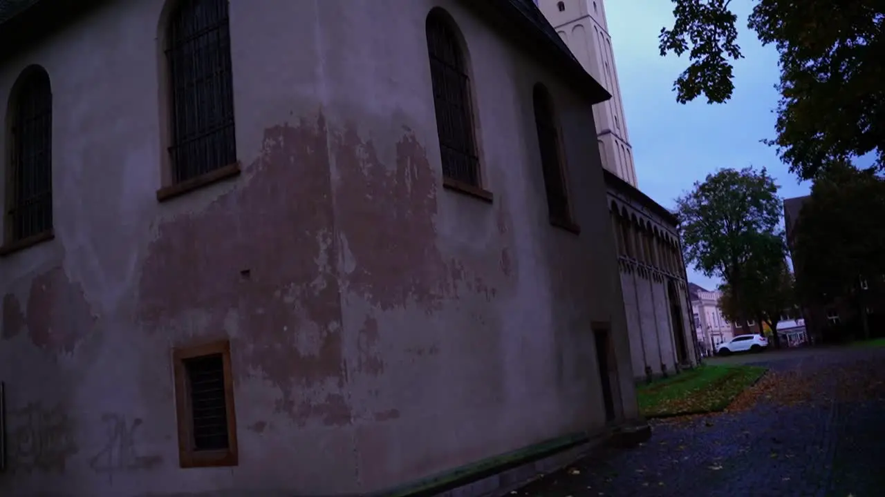 old horror house with white chipped plaster in the evening and large black windows