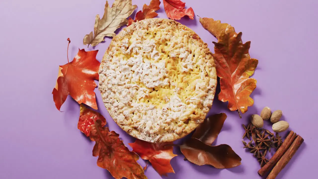 Video of autumn leaves spices and pie on purple background