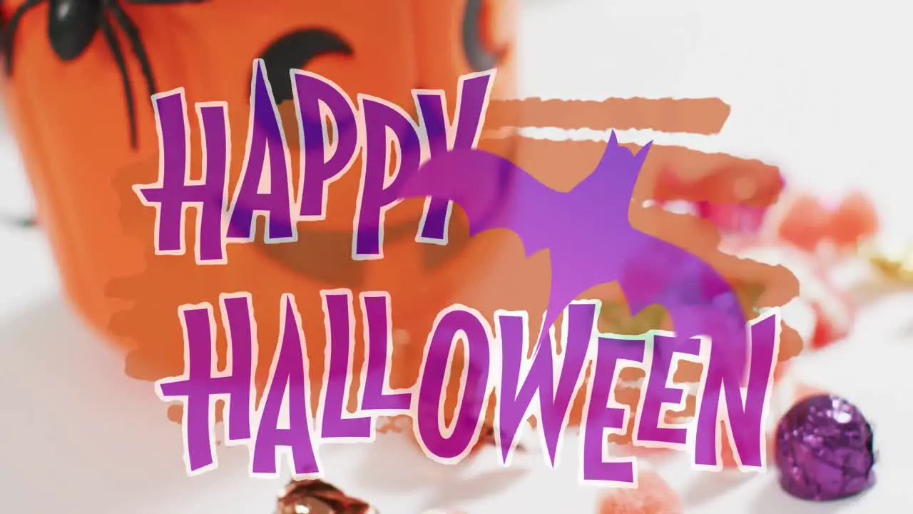 Happy halloween text banner with bat icon against pumpkin shaped bucket full of halloween candies