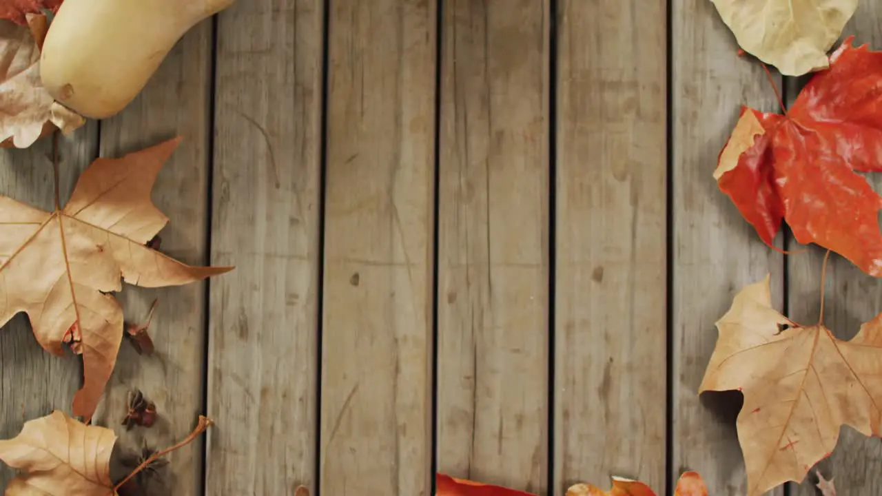 Video of pumpkins and autumn leaves on wooden background