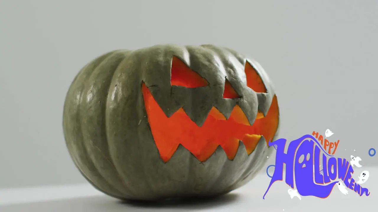 Happy halloween text banner over halloween scary pumpkin against grey background