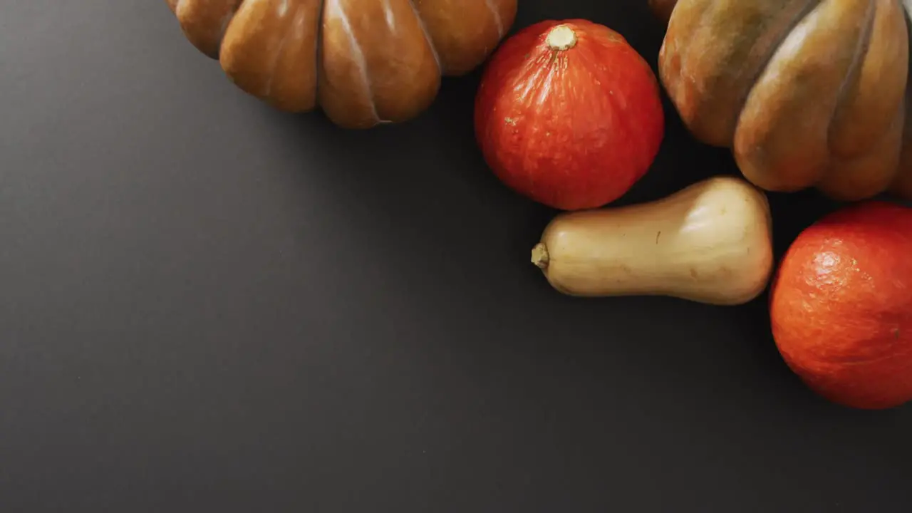 Video of multiple orange pumpkins lying on black background