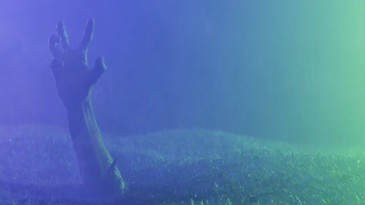 Video of hands raising from grass with smoke on black background