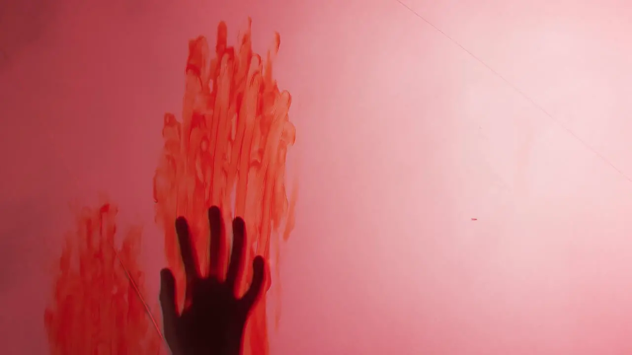 Video of silhouette of hand with blood stains moving on red background