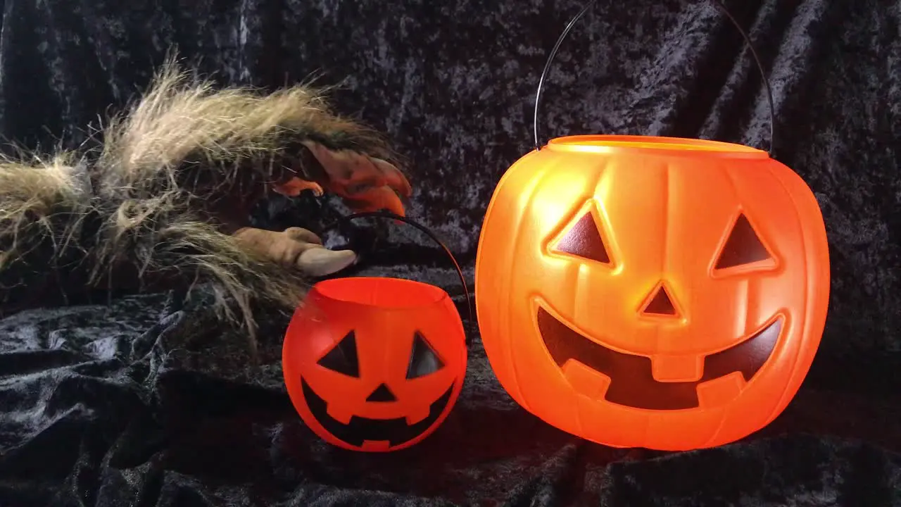 Monster arm grabs happy Halloween pumpkin pail and pulls it out of frame