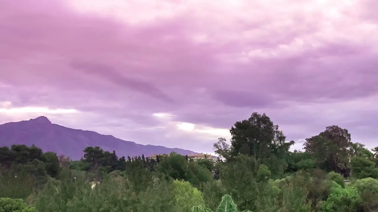 4k sinister flickering time lapse of purple clouds moving over trees and mountains filmed in marbella malaga spain