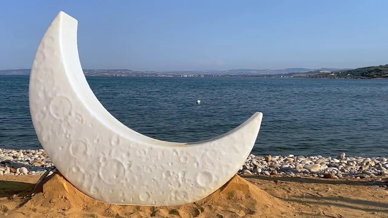 Half moon lamp on sandy beach in front of sea for preparation of venue decoration for celebration event