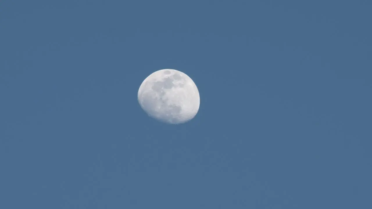 The moon glowing against a light blue sky