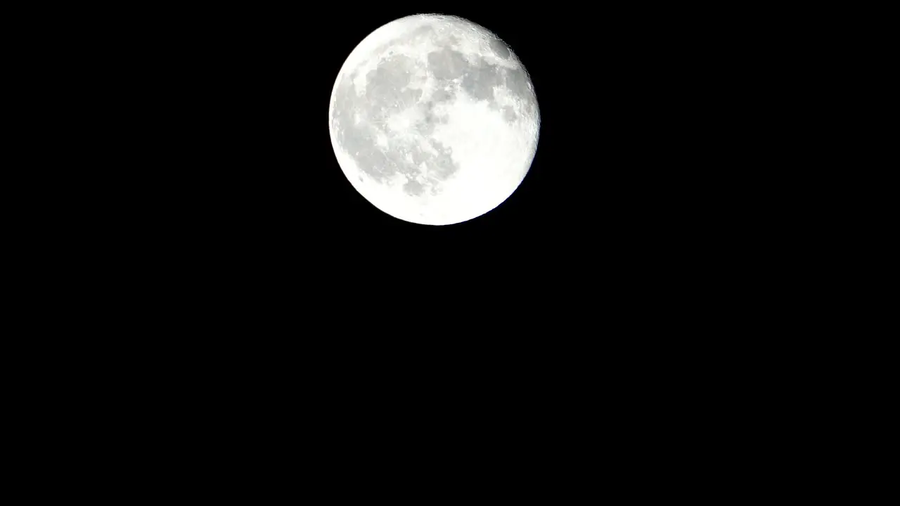 A telescopic and stationary view of the full moon on dark sky