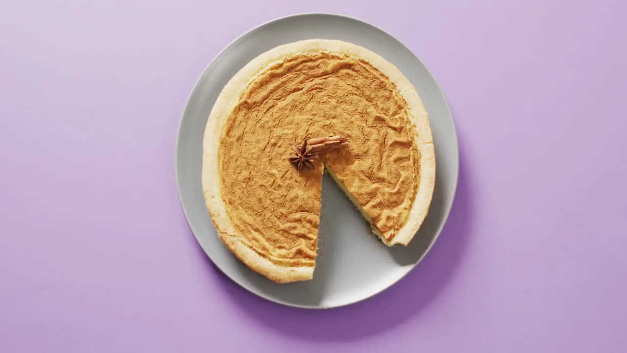 Video of pumpkin pie with spices on plate on purple background