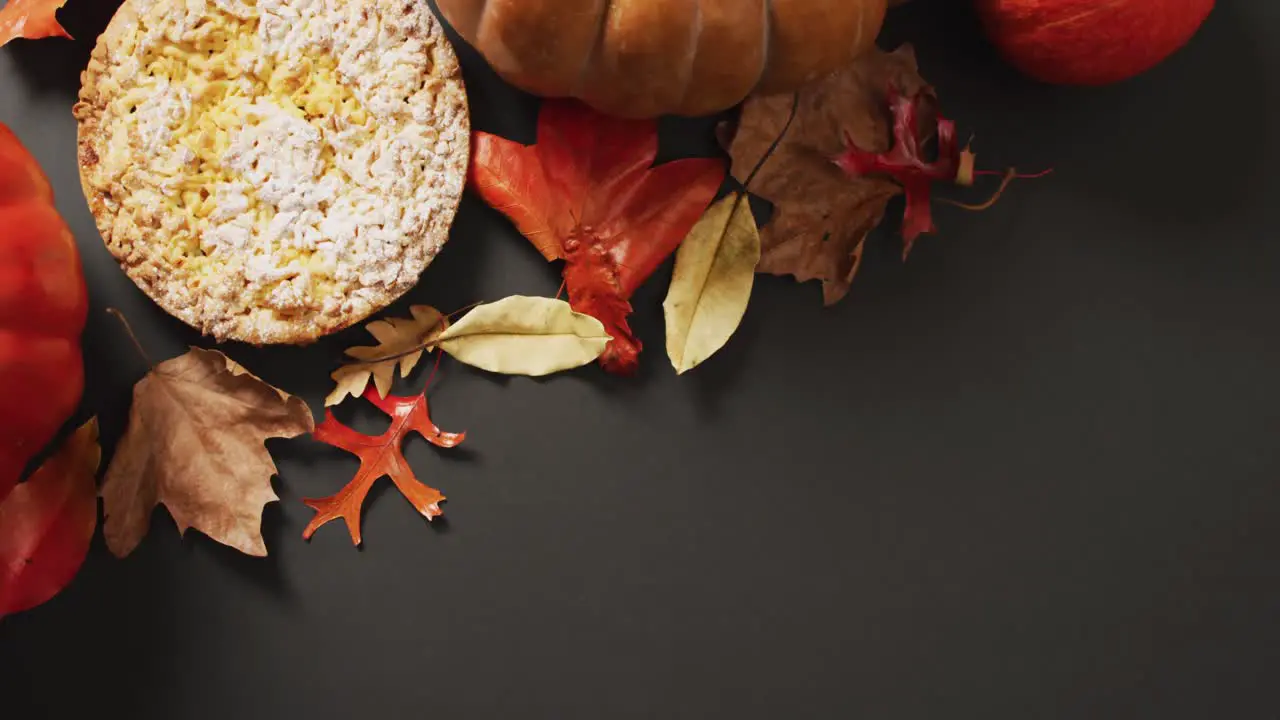 Video of autumn leaves pumpkin and pie on black background