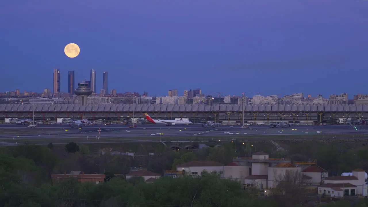 Full moon setting behind the Four Tower and International Airport in Madrid Spain