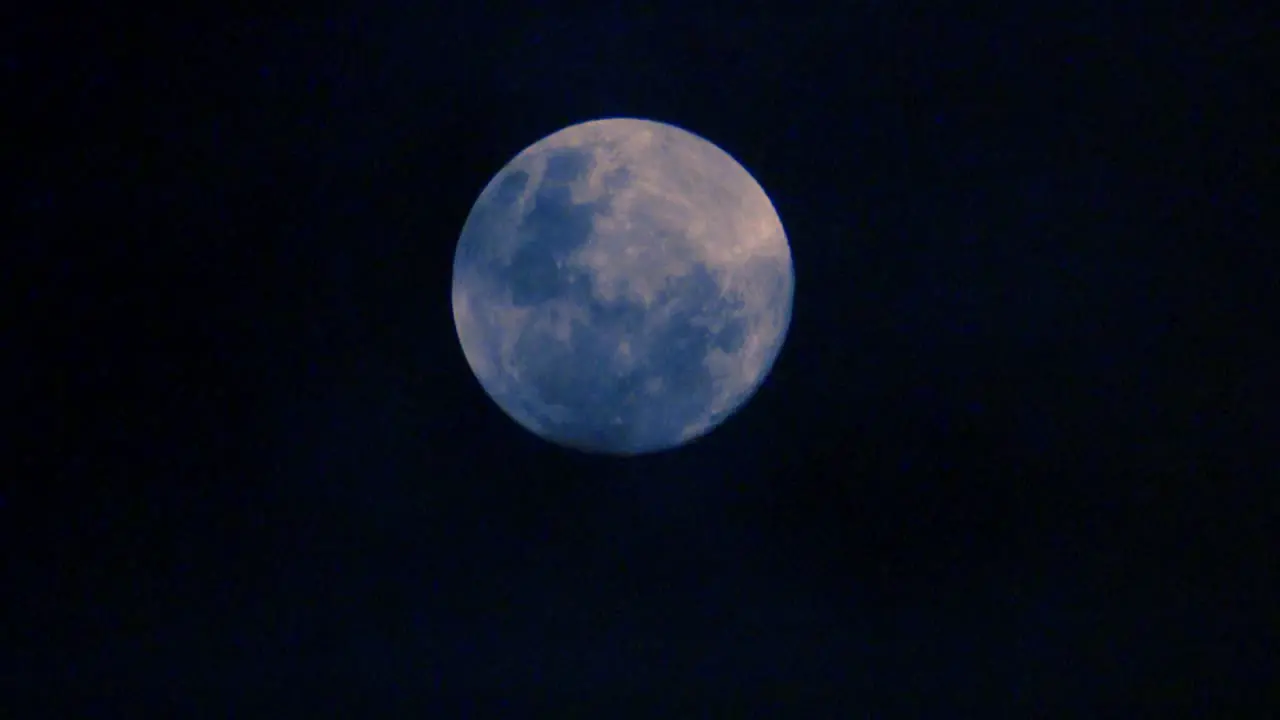 Clouds pass in front of a full moon creating an eerie perspective