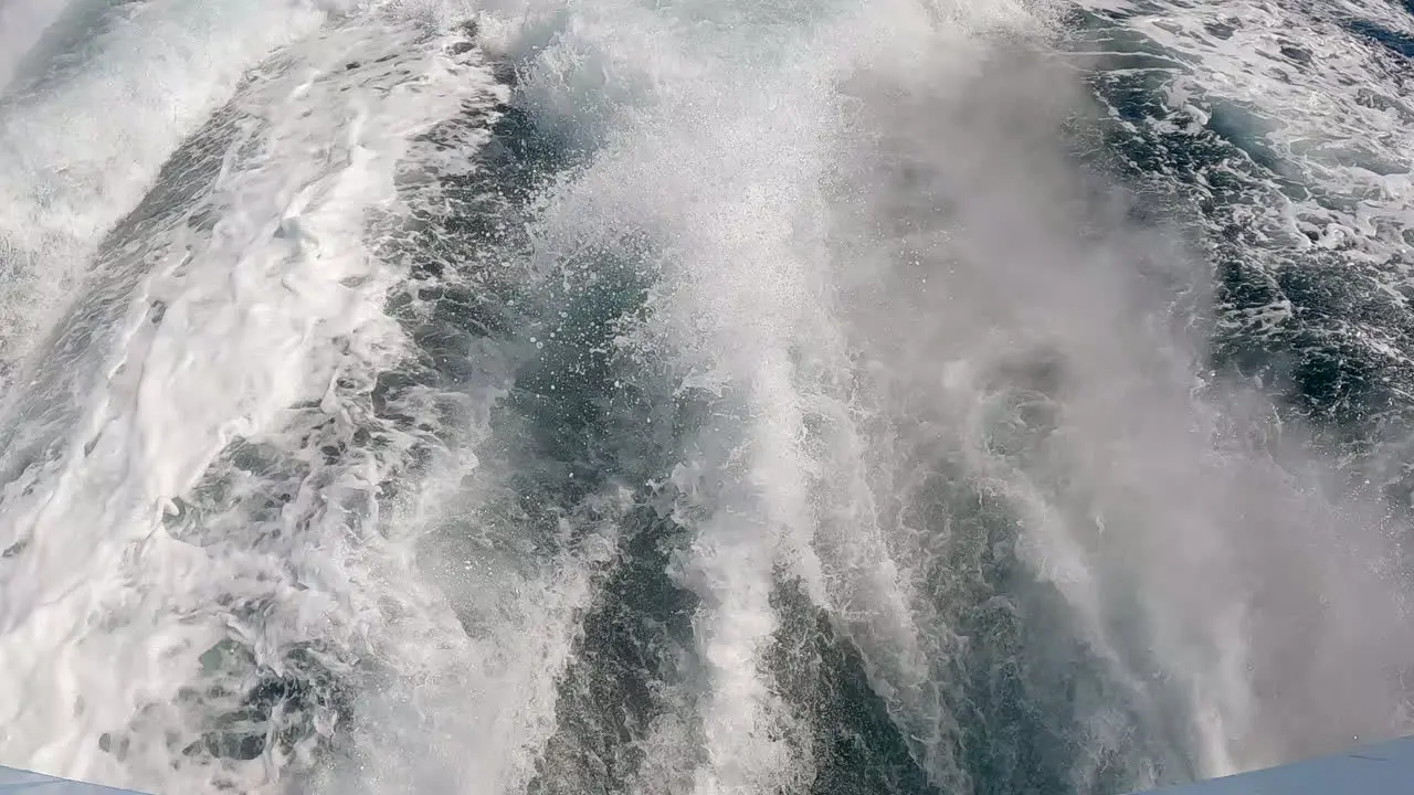 White water sea foam in the wake of a motorboat on the ocean water tilt up reveal of the pacific horizon in slow motion