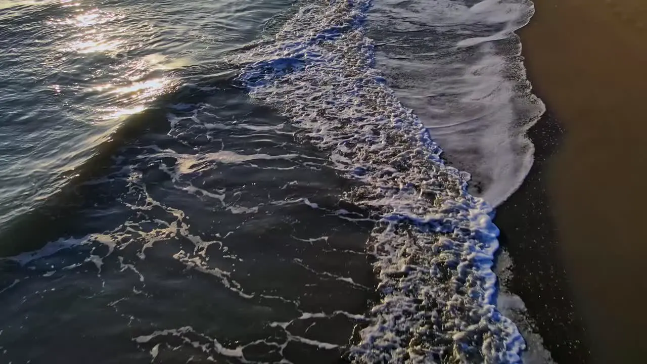 Aerial view of beach shoreline slowly moving forward and tilting up into the horizon