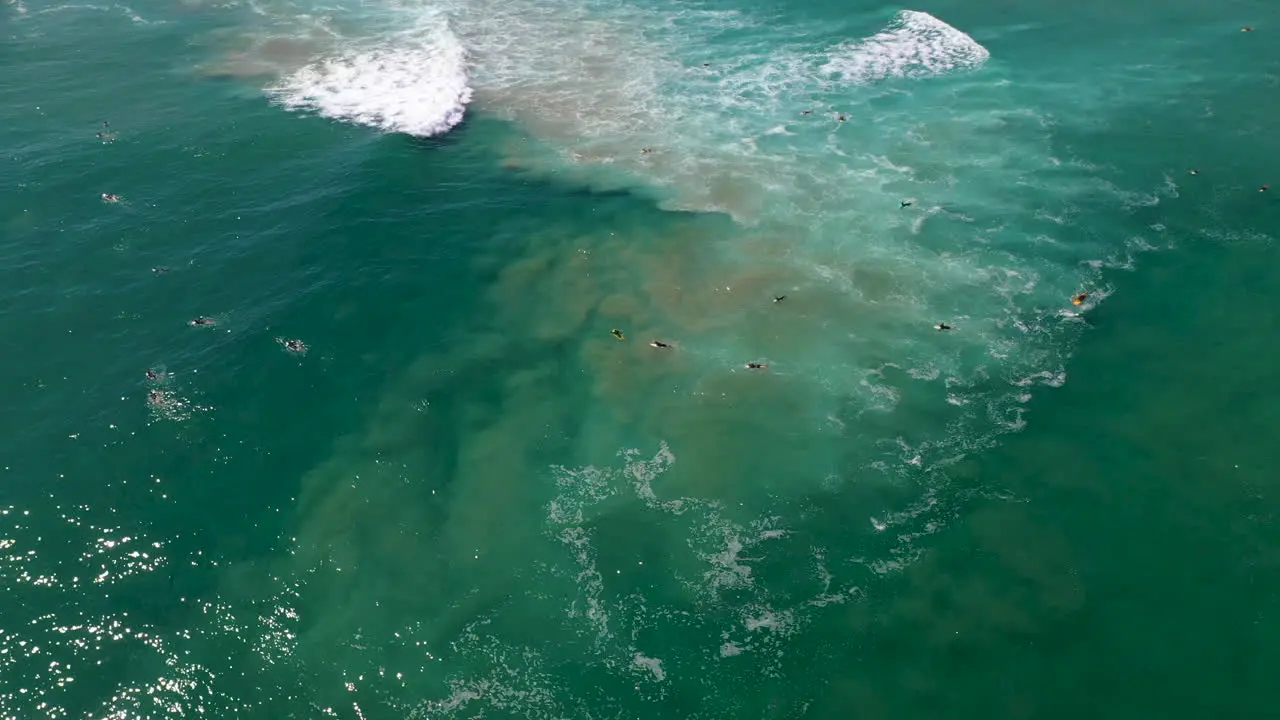 Rotating drone shot of surfers in the ocean waiting for a wave at Wategos Beach in Australia