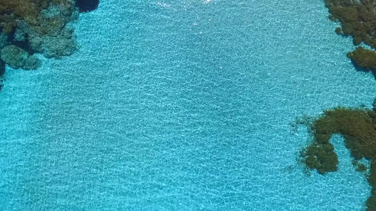 Aerial drone slow top down zoom in on a lagoon with clear blue tropical waters