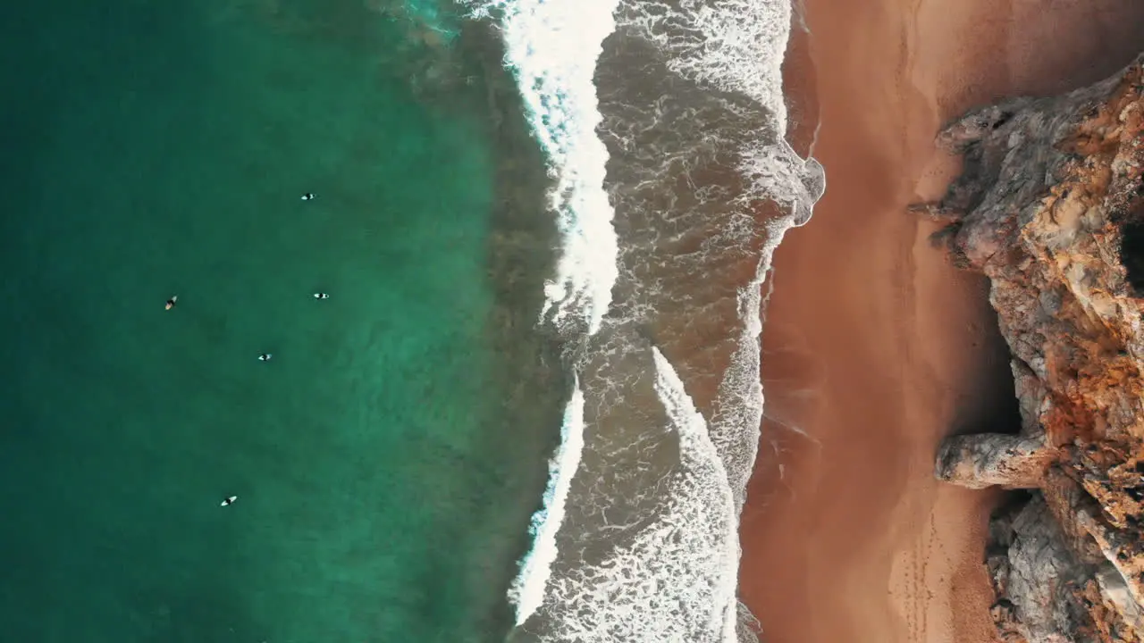 aerial shot from cliffs to the ocean with surfers waiting for a waves