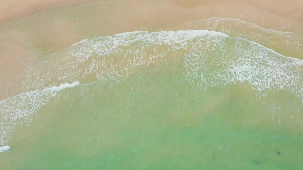 Top view of ocean waves crashing against an beautiful beach