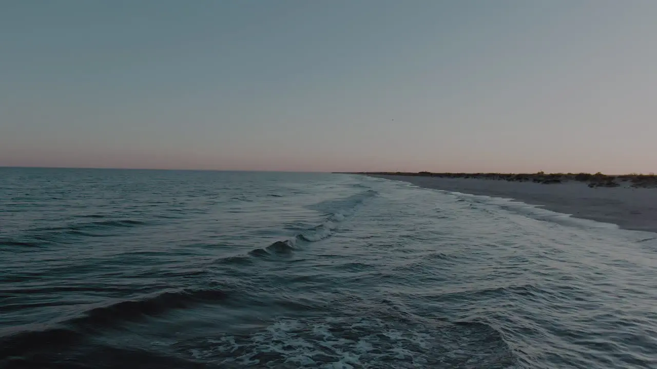 Low altitude drone shot flying forward over the mesmerizing waves hitting the white sand beach