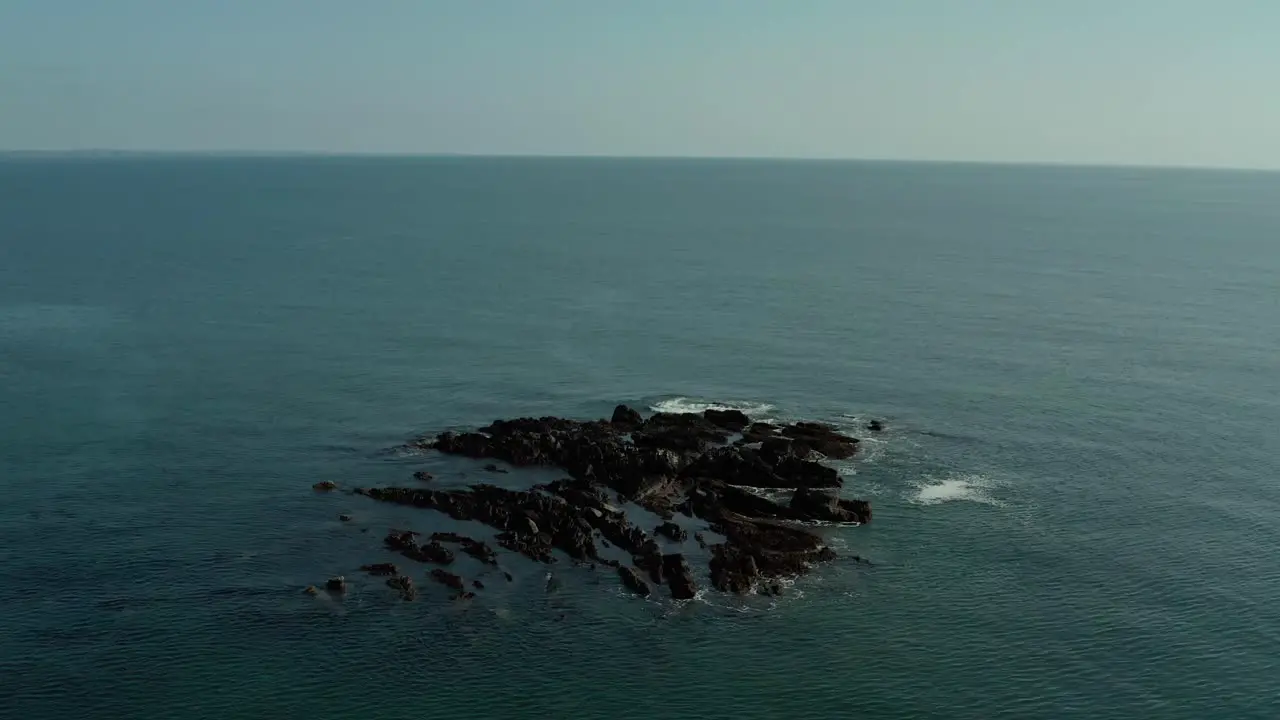 Drone shot of orbiting around rocks in middle of ocean at day