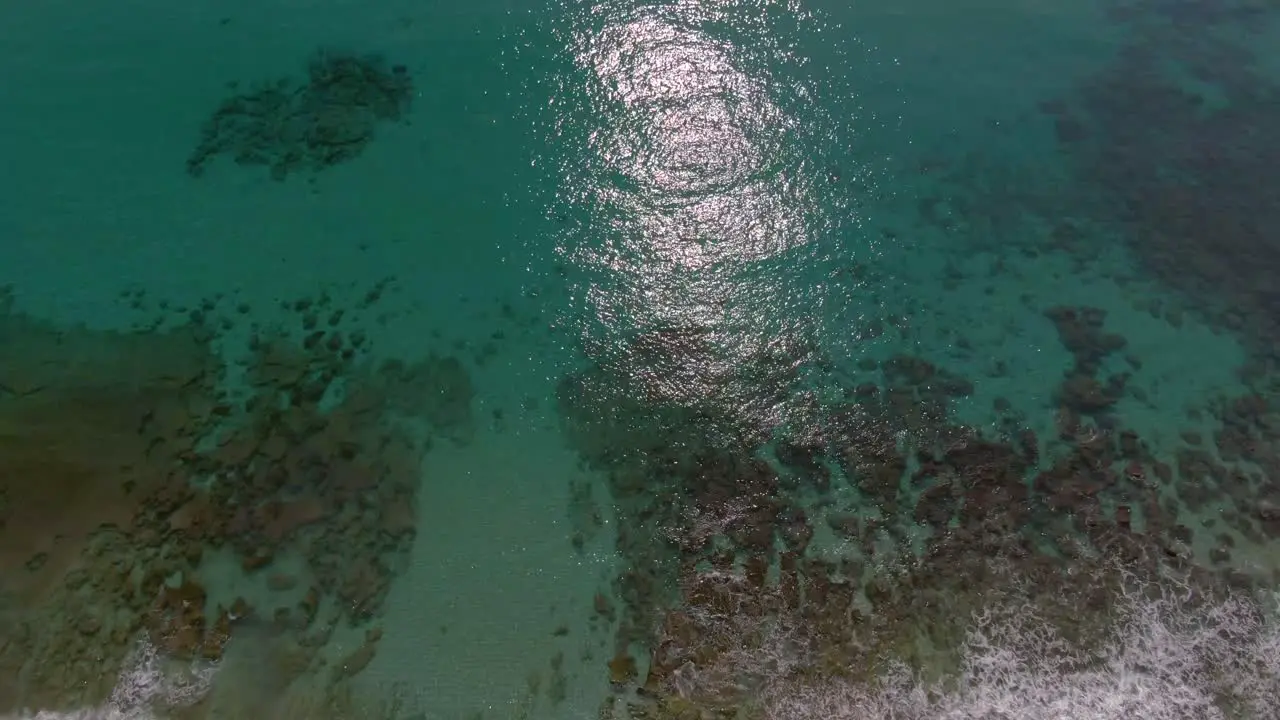 Drone tilt up over pristine Amami Beach reveals turquoise ocean and reef