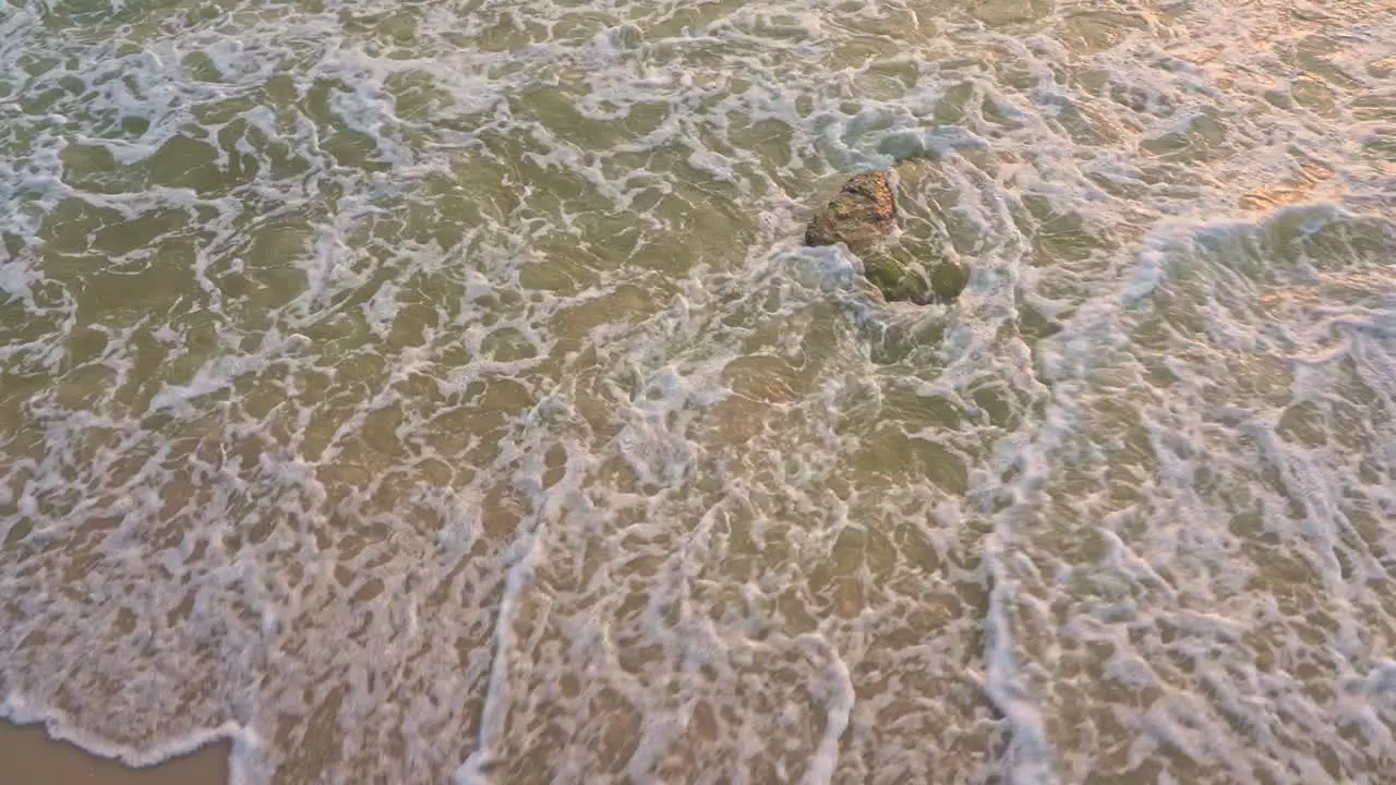 Slowmo Closeup Mesmerizing ebb and flow of waves on a beach with pink sand and turquoise waters