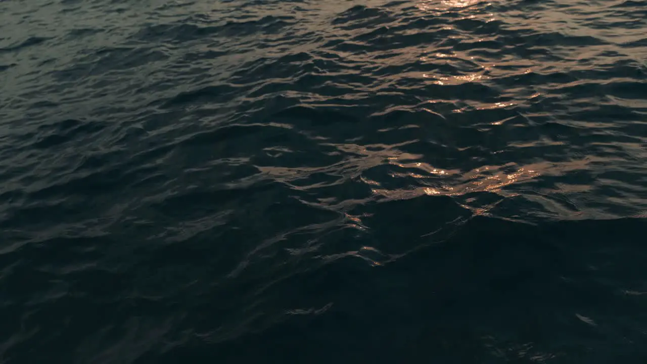 Slow motion shot of golden sun reflecting during sunset in water waves of blue ocean