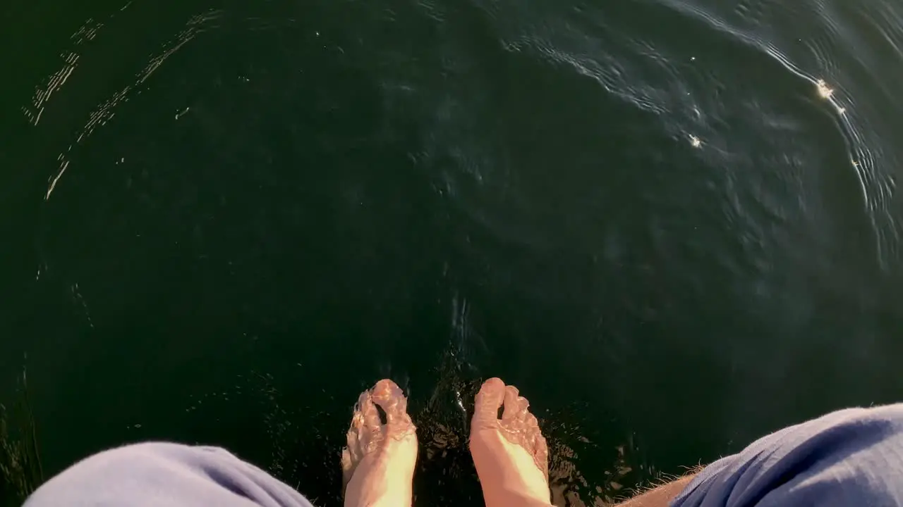 First-person perspective view of relaxing feet on the lake water