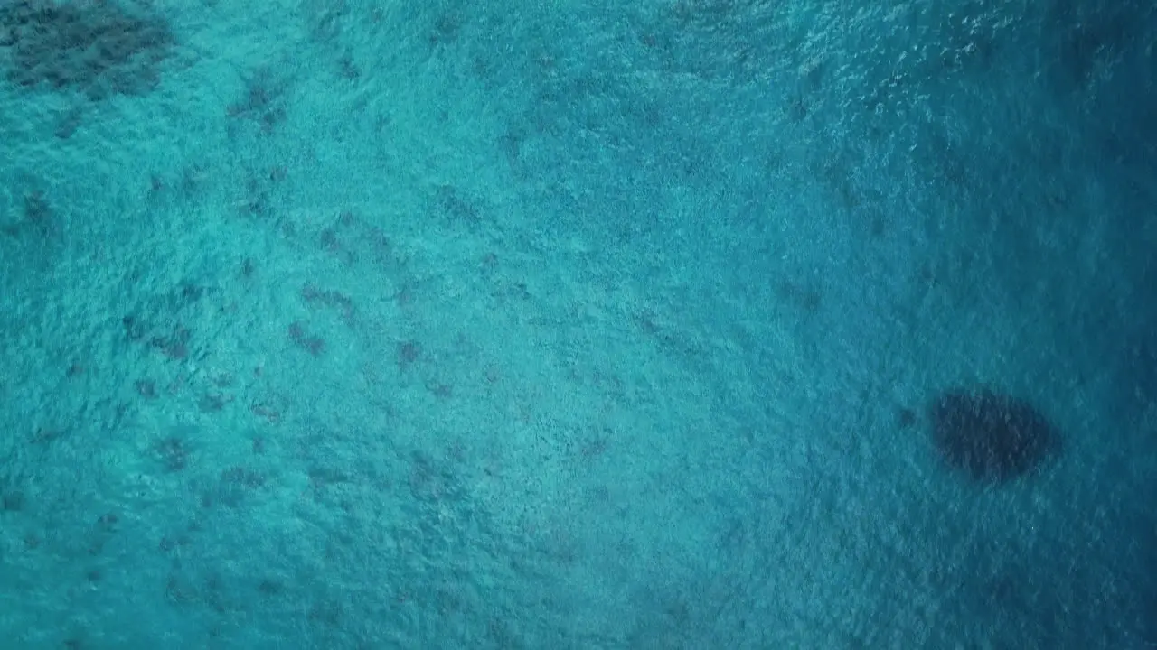 Aerial flyover above blue tropical ocean water