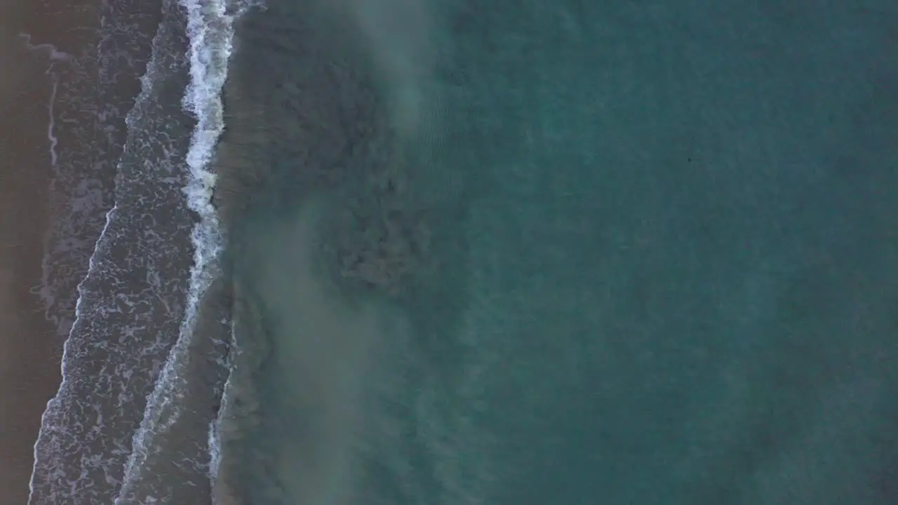 drone view of tropical beach a bird's eye view of ocean waves crashing against an empty beach from above