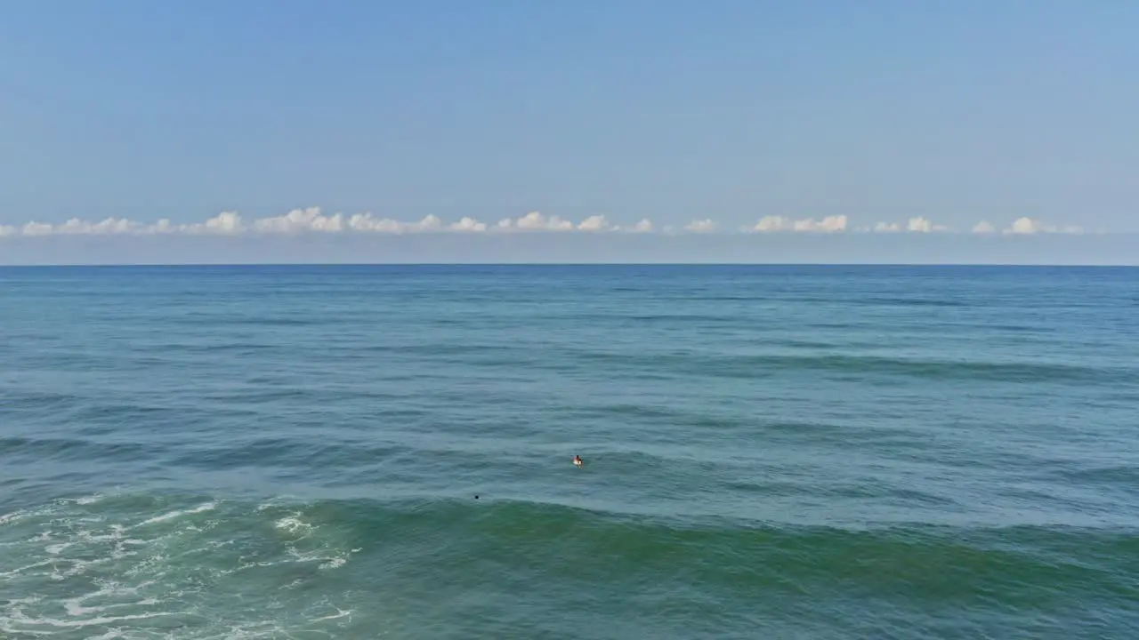 Aerial surfers paddling over waves and sitting observing ocean