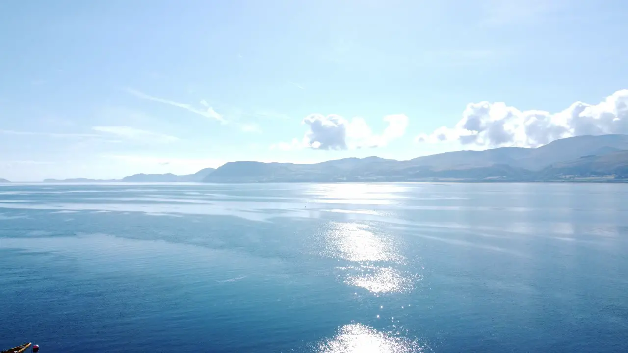 Shimmering brilliant blue ocean with scenic Snowdonia mountains across the horizon aerial view