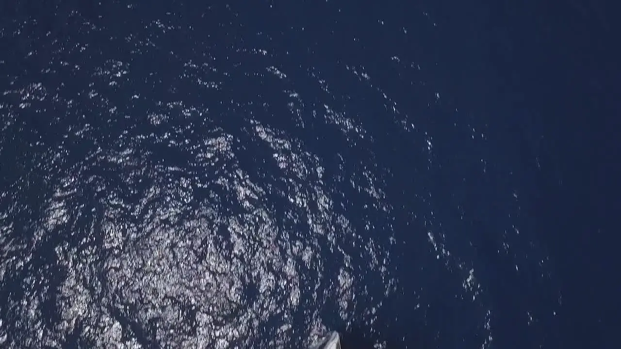 Aerial top-down forward over sailboat on blue sea